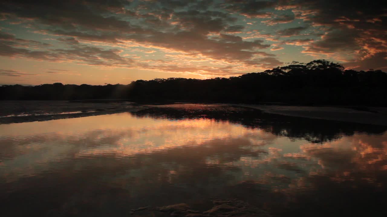 日落的实时视频在Coffs Creek泥滩与金色的倒影在涟漪的水，Coffs港，新南威尔士州，澳大利亚。视频下载