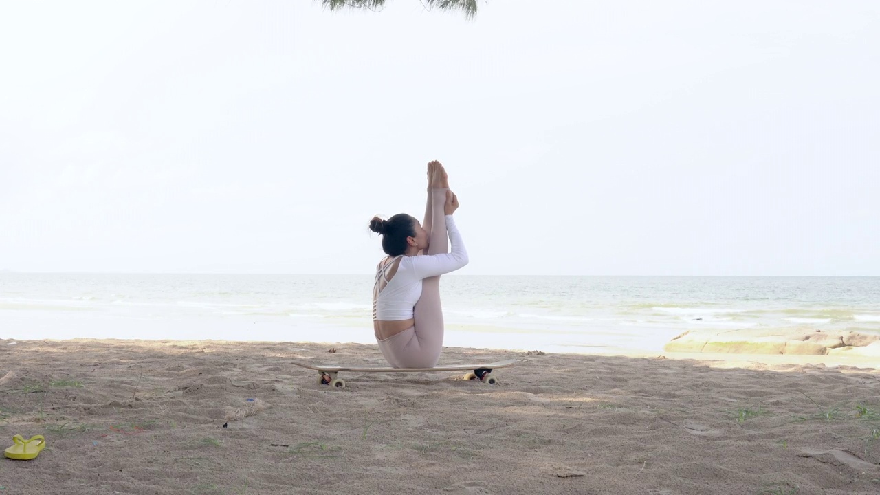 美丽的女人穿上运动服在日出的早上在海滩上练瑜伽。视频素材