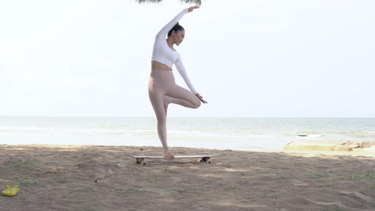 美丽的女人穿上运动服在日出的早上在海滩上练瑜伽。视频素材