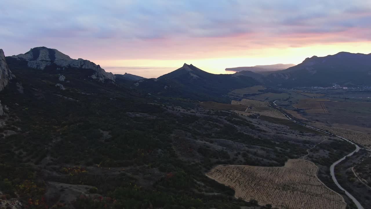 明亮的晚霞在多云的天空下越过山脉和葡萄园在一个山谷视频下载