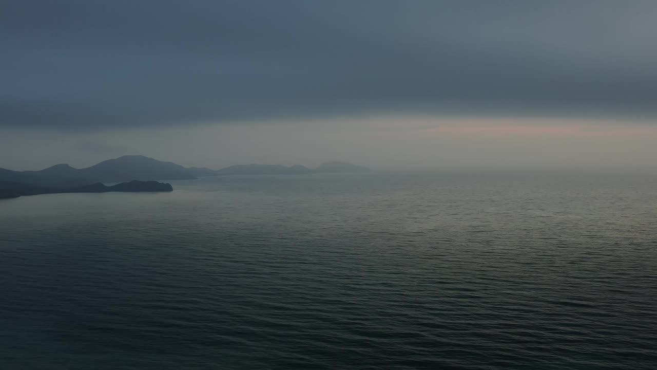 飞机在黎明前的薄雾中飞过海面，撞向山头，坠入大海。大自然的神奇视频下载