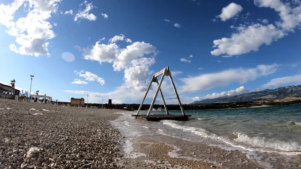 在Zrće，帕格，克罗地亚，海浪撞击一个荒芜的海滩的一个秋千背景的特写视频下载