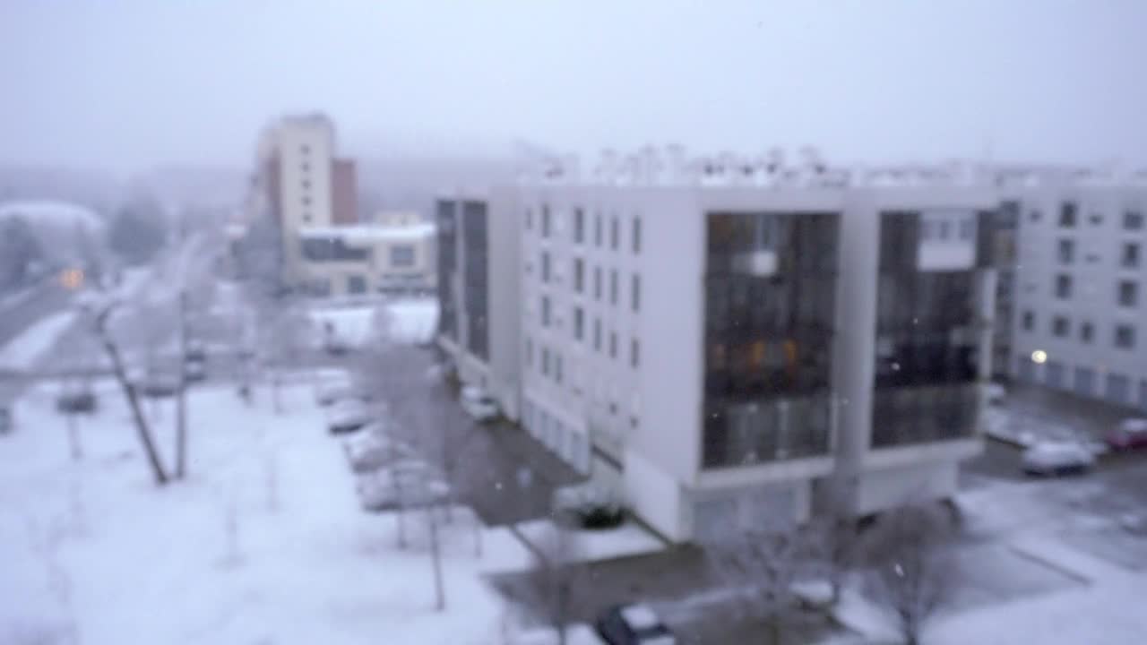 聚焦雪花飘落，背景是模糊的建筑视频下载