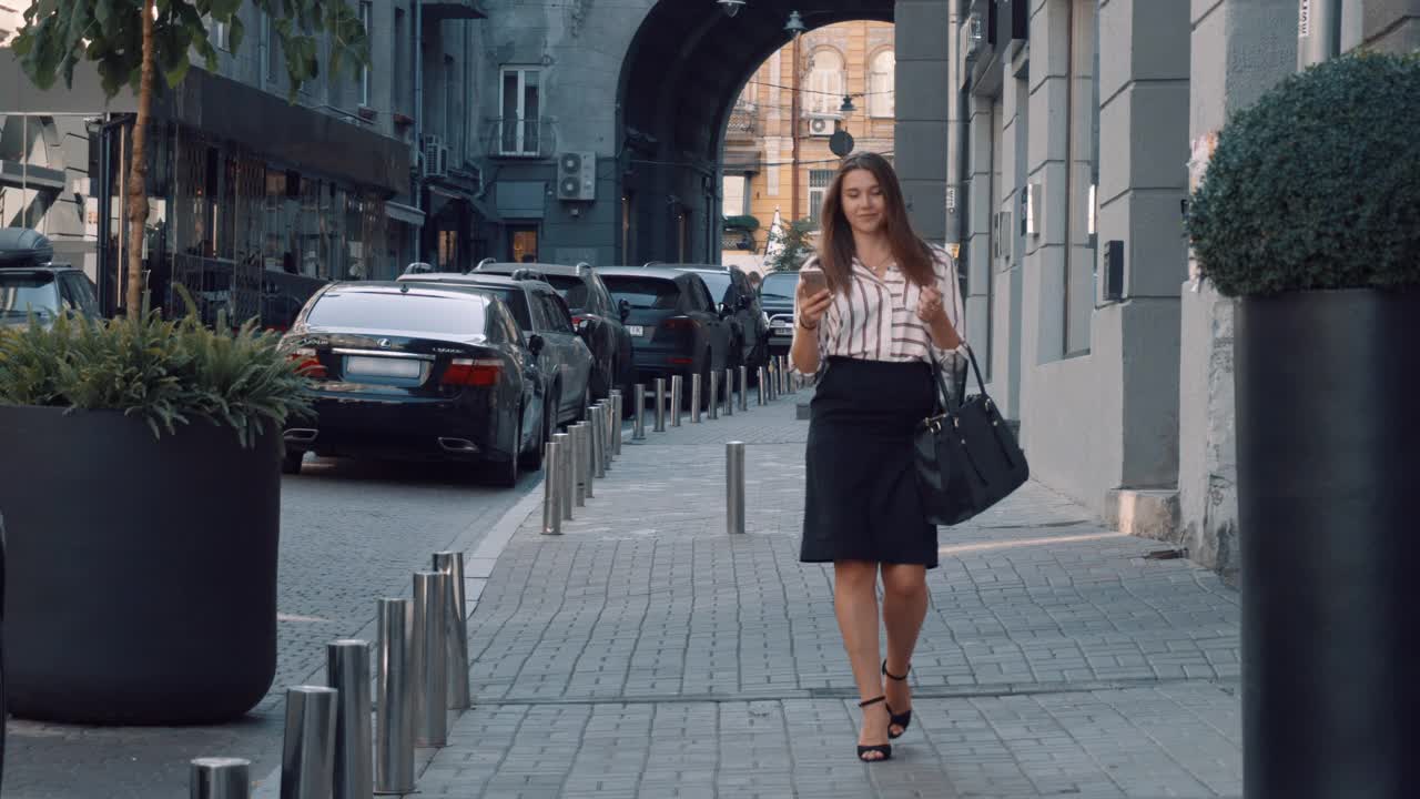 迷人的白人年轻女人在电话，而购物走在城市街道视频素材