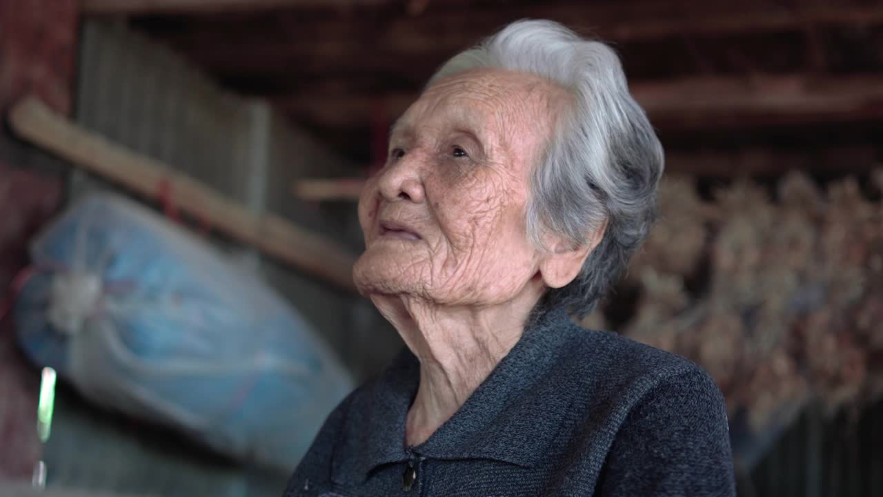 亚洲老年妇女，头，肩的观点，一个老年妇女坐在家里在泰国的农村，老年妇女的概念视频下载