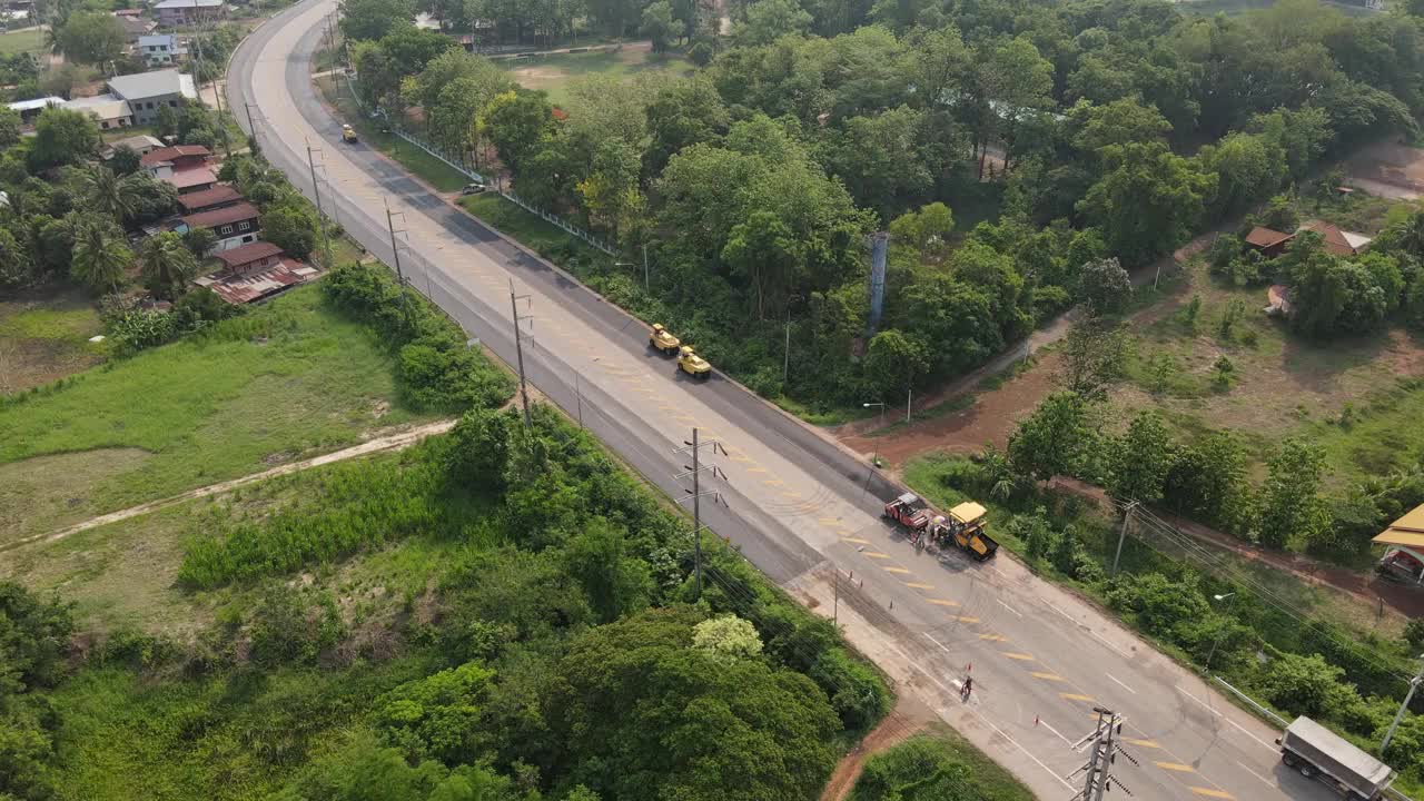 俯视图或鸟瞰图上的压路机工作在道路施工现场使用沥青修复道路，4k视频视频下载