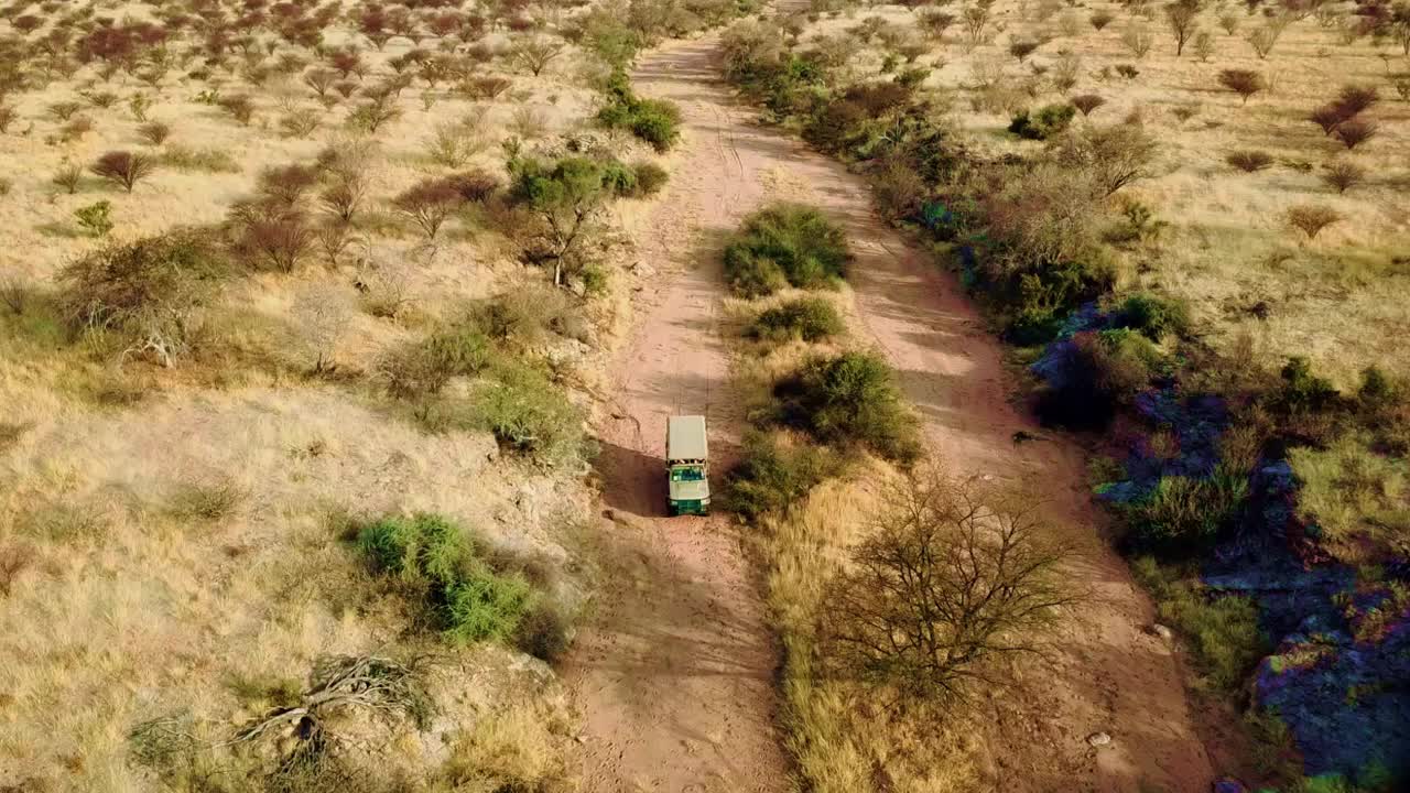 无人机视频显示，一辆4x4越野汽车在非洲大草原的沙地上行驶。视频下载