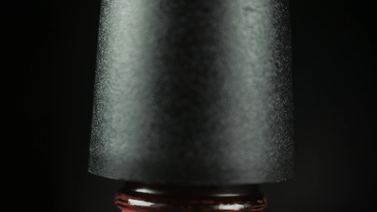在美容院用开瓶的红色凝胶指甲油，用刷子滴一滴到罐子里。黑色背景。特写镜头。视频下载