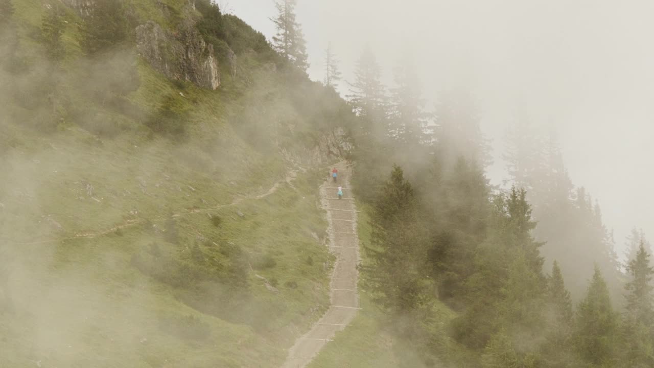 一群徒步旅行者在美丽而朦胧的奥地利阿尔卑斯山上爬楼梯-中镜头视频下载