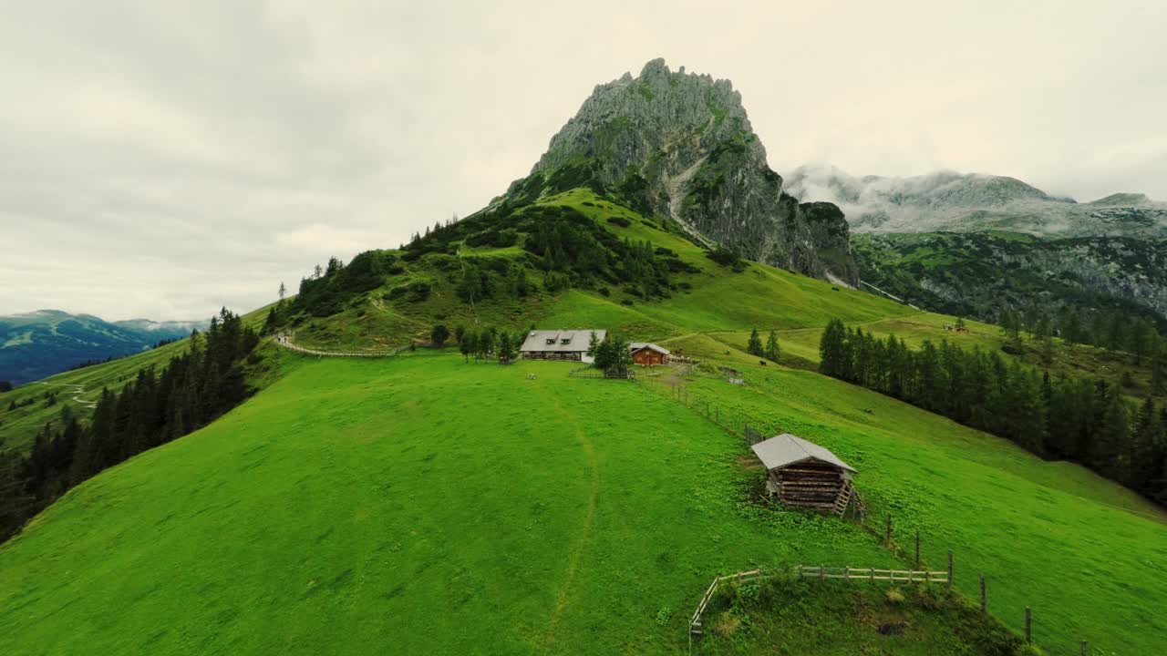 全景航拍风景如画的山小屋在奥地利阿尔卑斯山。山峰被云覆盖在背景中视频下载