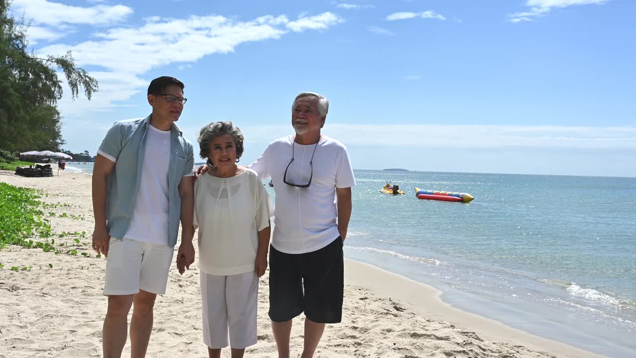 快乐的亚洲资深情侣与家人在海滩上旅行。视频下载