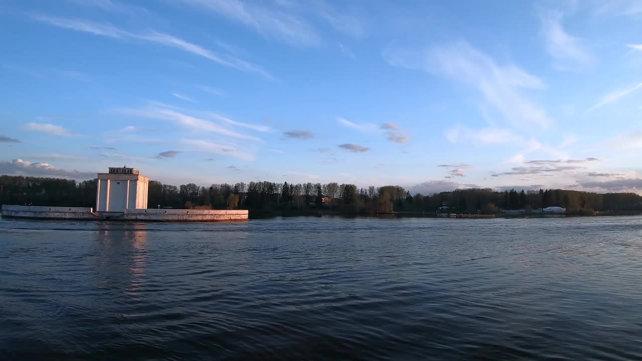 日落时分，一艘大型客轮在河上通过。美丽多彩的风景映衬着日落时的蓝天。在河上乘船旅行。视频下载