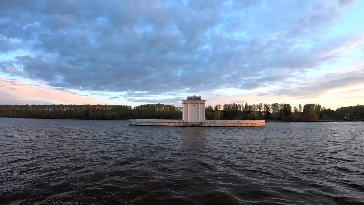 日落时分，一艘大型货船在河上通过。美丽多彩的风景映衬着日落时的蓝天。沿河船运货物运输视频下载