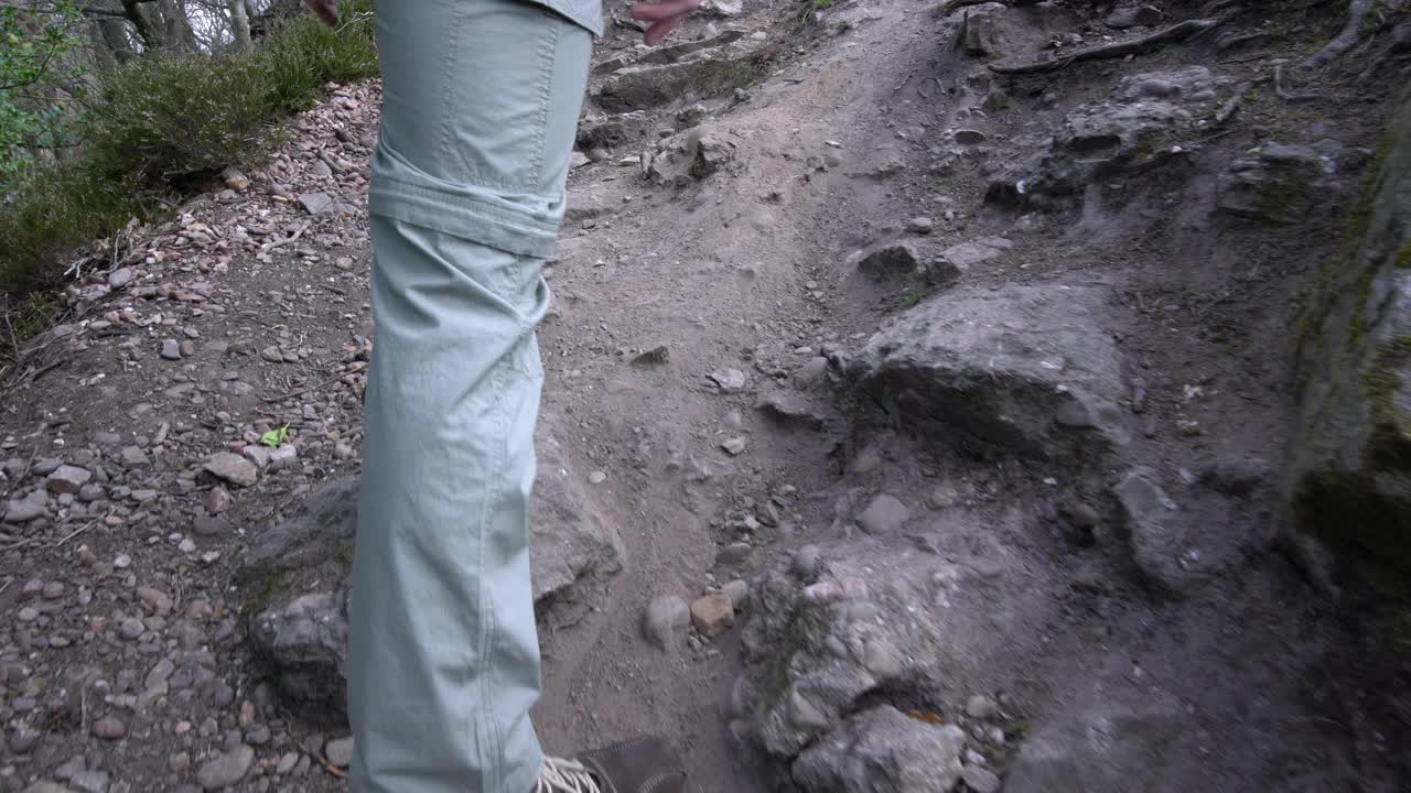 让徒步旅行者走在森林的小上坡路-鞋的特写视频下载