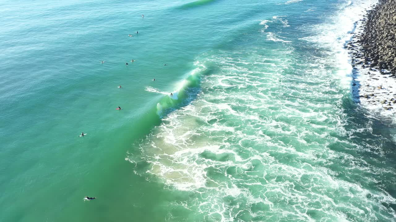 鸟瞰柔和的日出和海水，人们在山脊周围冲浪视频下载