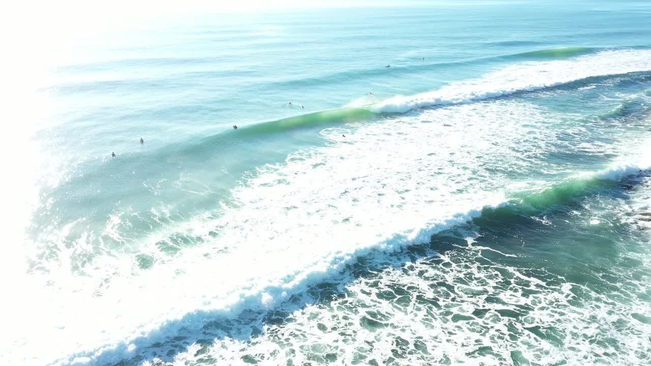 鸟瞰柔和的日出和海水与人们冲浪视频下载