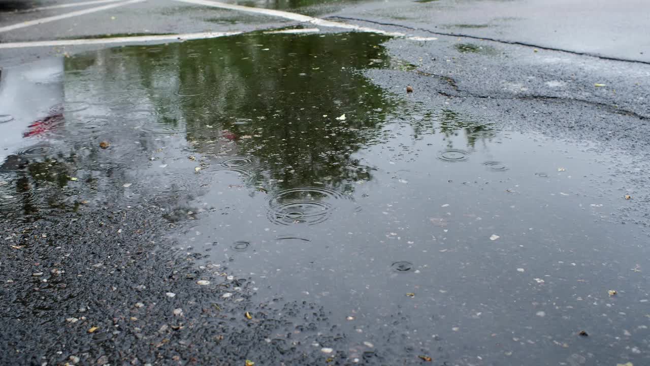 沥青路上的水坑里下着雨视频下载