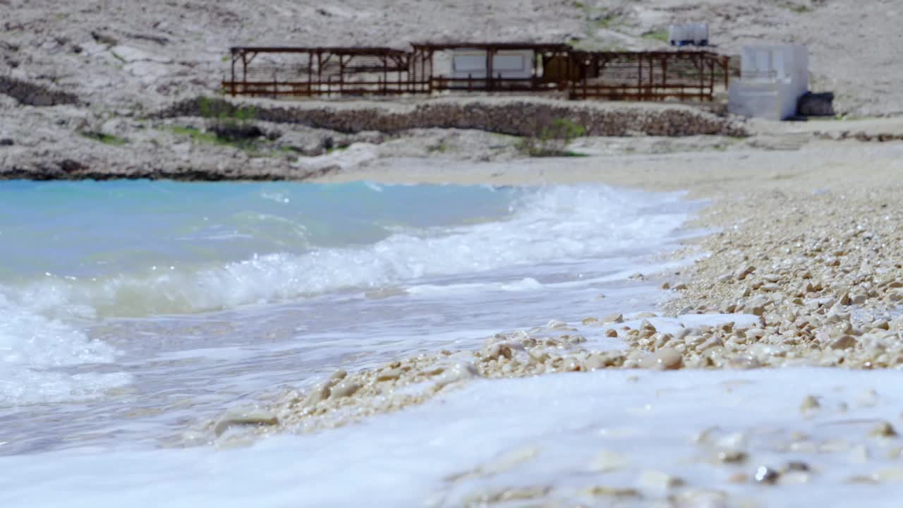 海浪撞击一个空的，荒芜的，卵石海滩在帕格，克罗地亚的特写视频下载