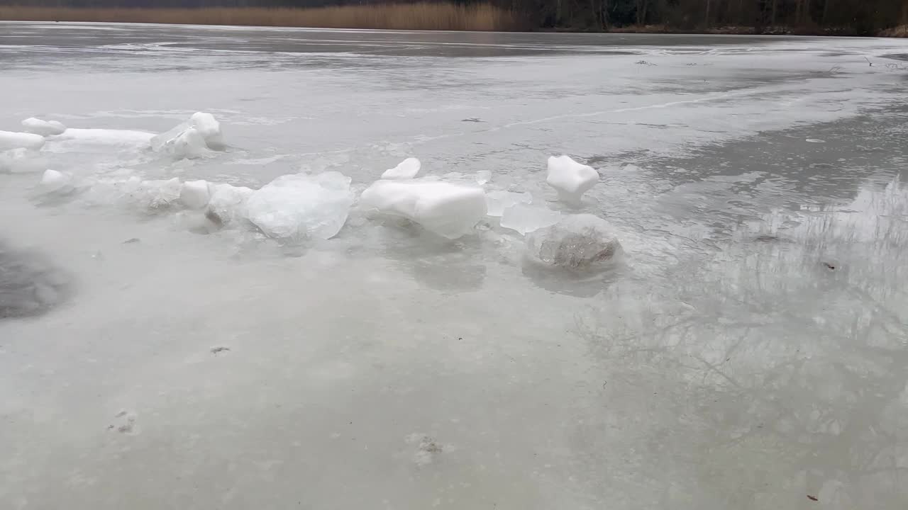 池塘内有一洞冰，周围有冰雪浮冰，从右向左看，大自然在冬天，大自然在美丽视频下载