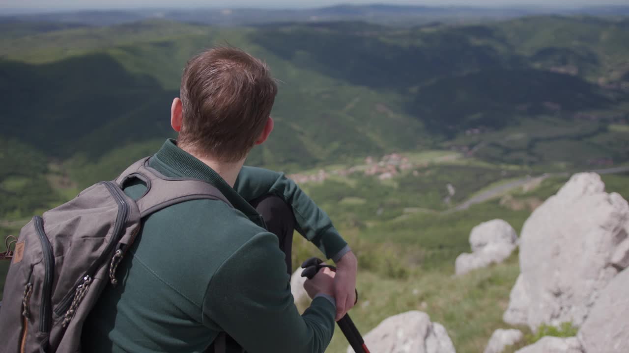 背着背包的成熟男人在山顶欣赏风景视频素材