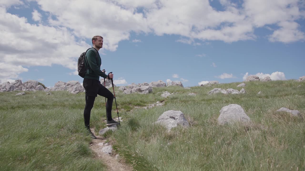 背着背包的成熟男人在山顶欣赏风景视频素材