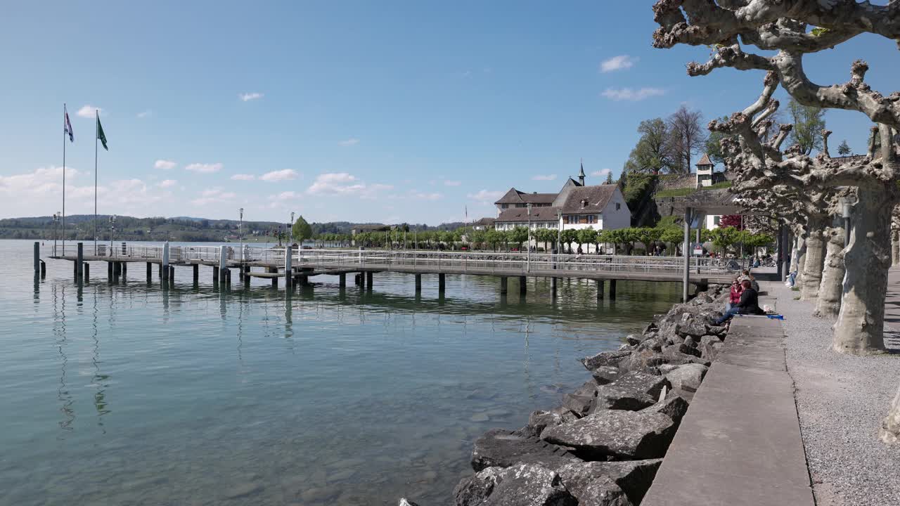 rapperswil、瑞士。03. 2021年:空的平台上有湖步道，人们坐在水面上，在白天的阳光下放松视频下载