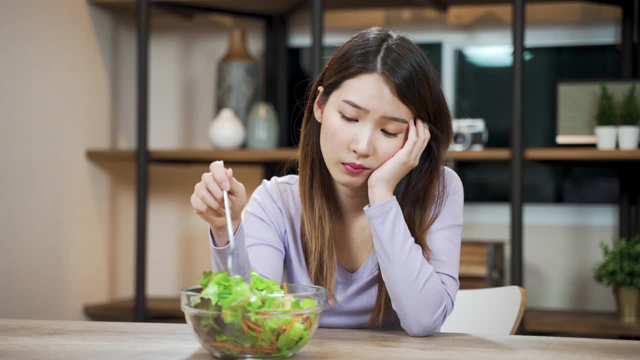 无聊的亚洲女人不喜欢吃蔬菜沙拉视频素材