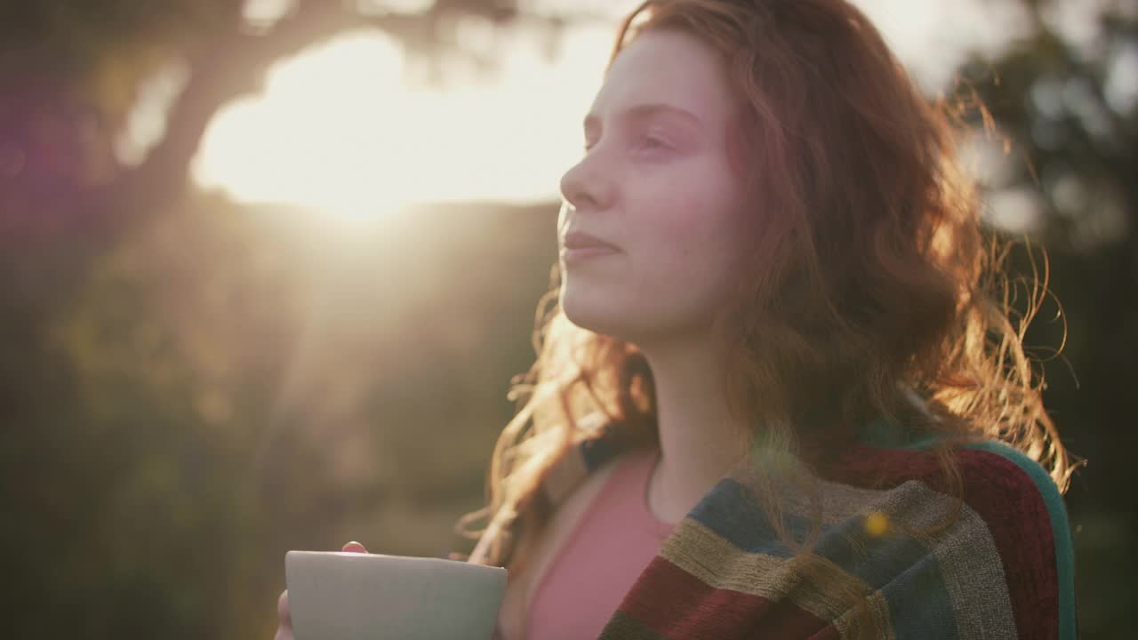 女人拿着茶杯在花园里微笑视频素材