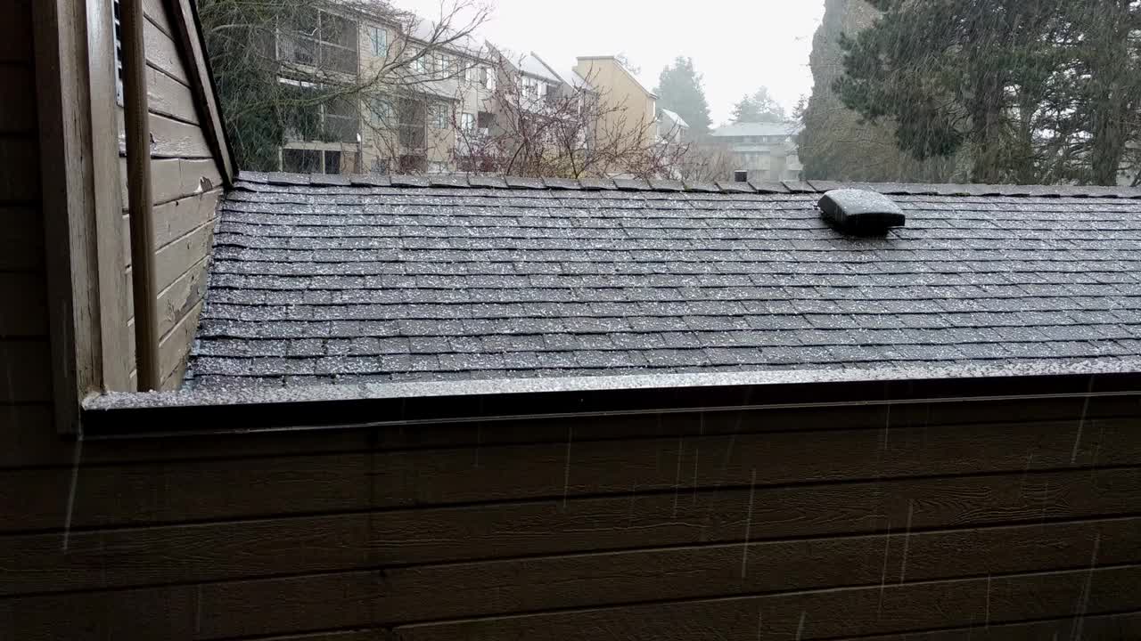 一场带冰雹的冰雹正落在一户人家的屋顶和甲板上。视频下载