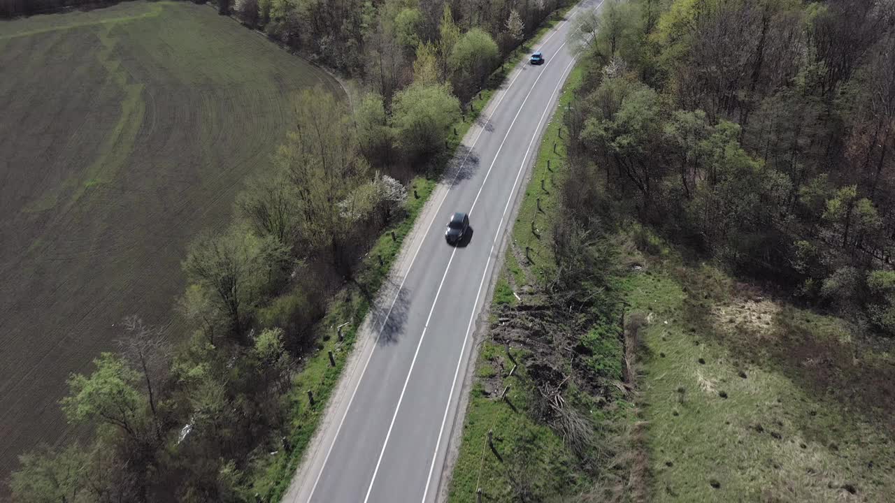 鸟瞰图汽车行驶在空旷的道路上，沿着树木和田野在阳光明媚的早晨。旅行，汽车租赁，保险概念视频素材