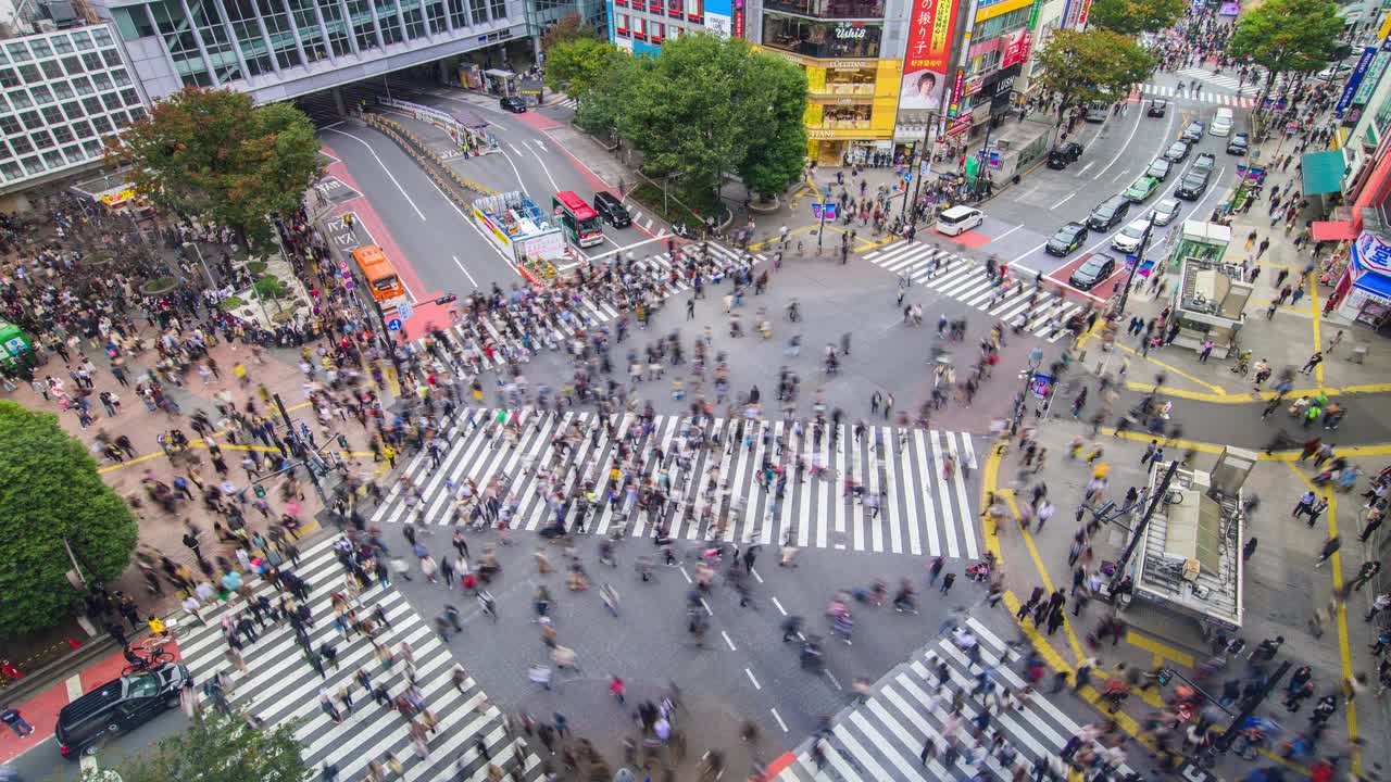 从空中看涉谷路口，许多行人和车辆在白天穿过日本东京的交叉路口。涉谷时尚购物娱乐理念视频下载