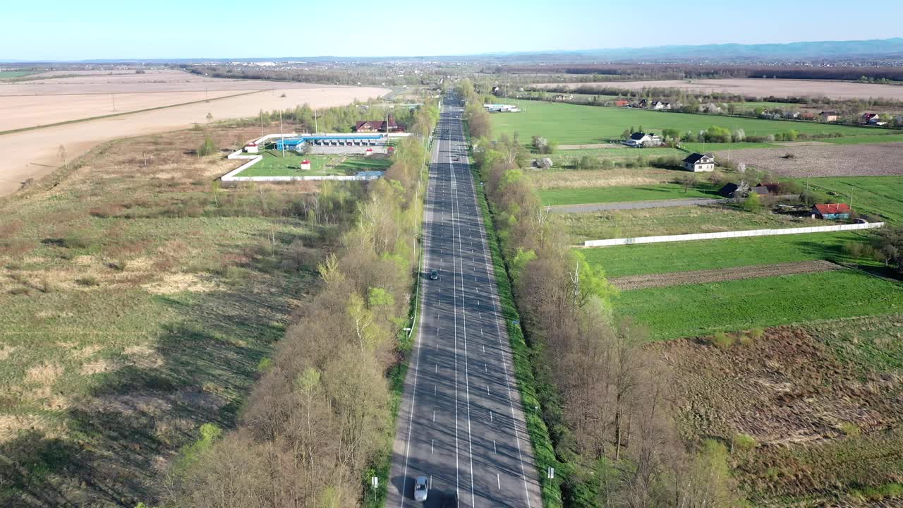 鸟瞰图上的汽车行驶在空旷的道路上，沿着树木和田野视频素材