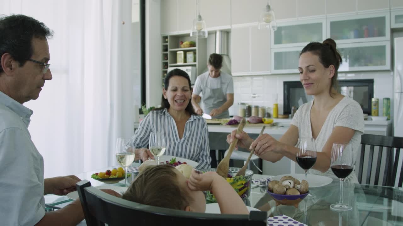 年轻的成年人坐在餐桌前为家人提供健康食品视频素材