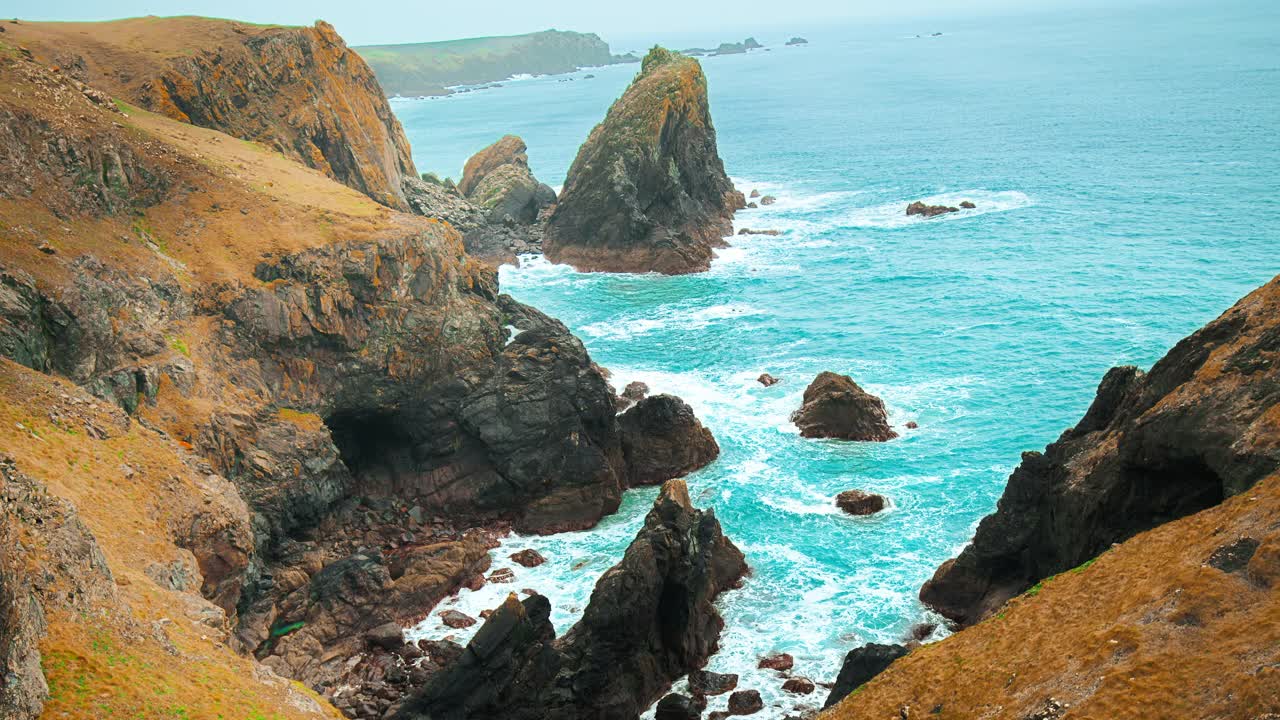 透明的海洋蓝绿色海浪冲击海岸岩石悬崖在4K。视频素材