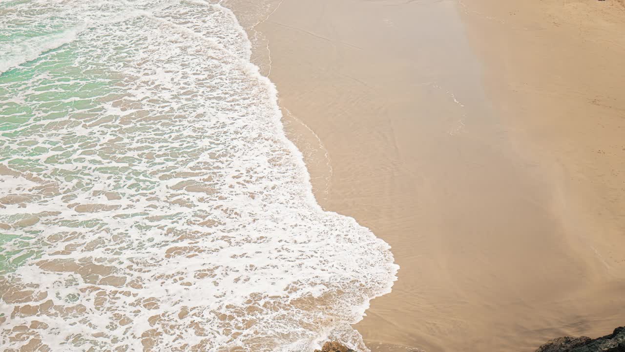 透明的海洋，蓝绿色的海浪撞击着沙滩的慢镜头。视频素材