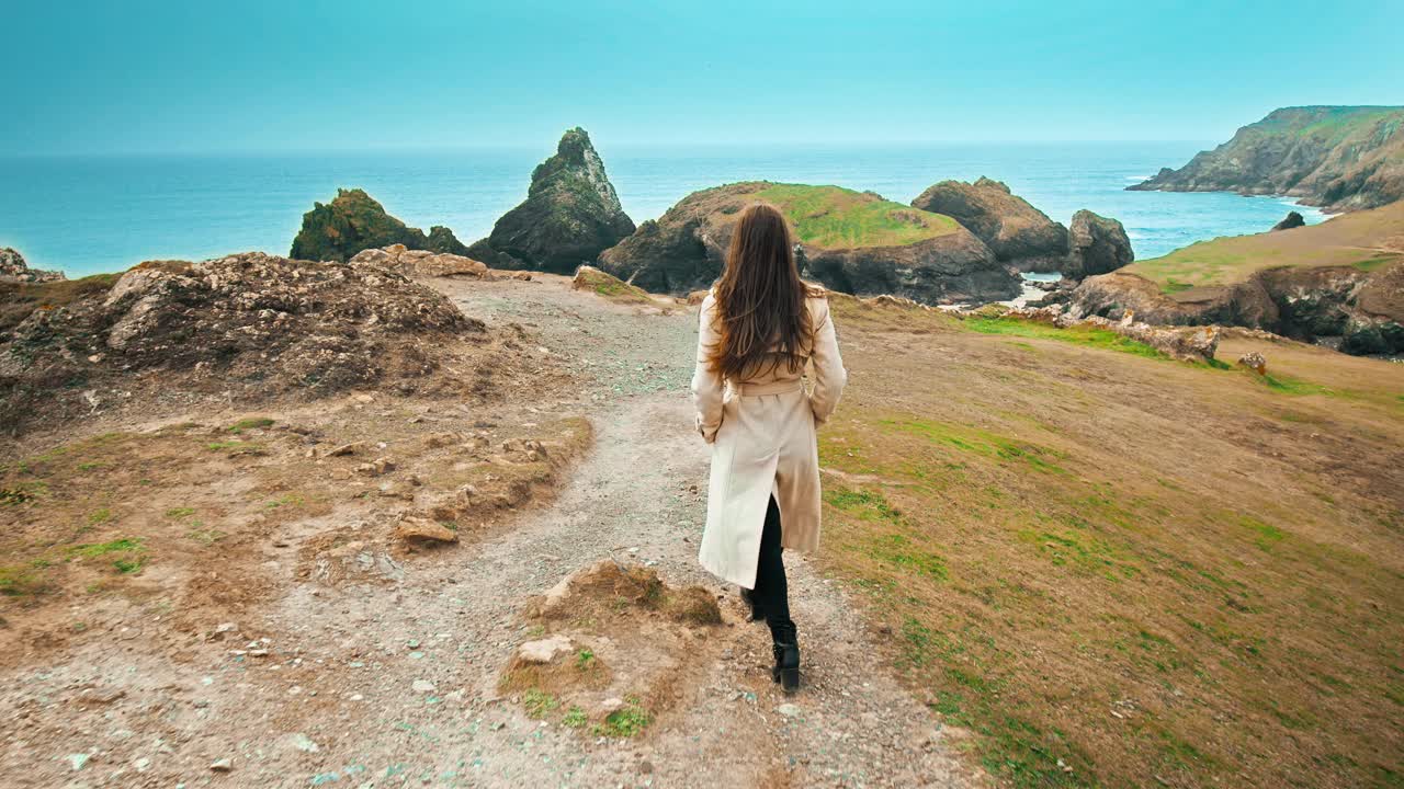 穿着优雅的年轻女子，穿着大衣，走在金尼斯湾欣赏风景。视频素材