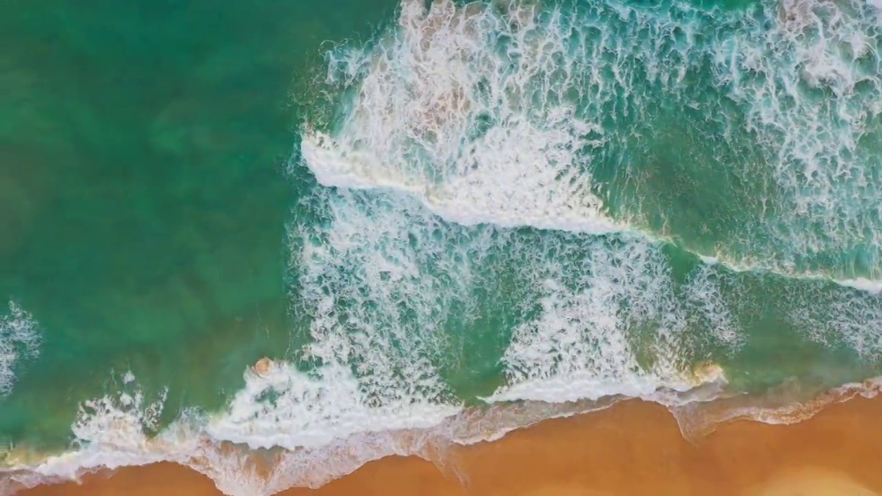 鸟瞰蔚蓝的大海，海浪拍打着沙滩。视频素材