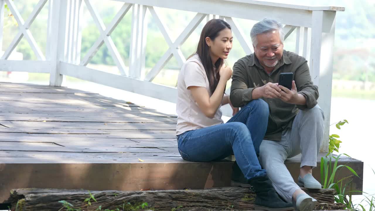 亚洲老人用手机和女儿在公园自拍视频素材