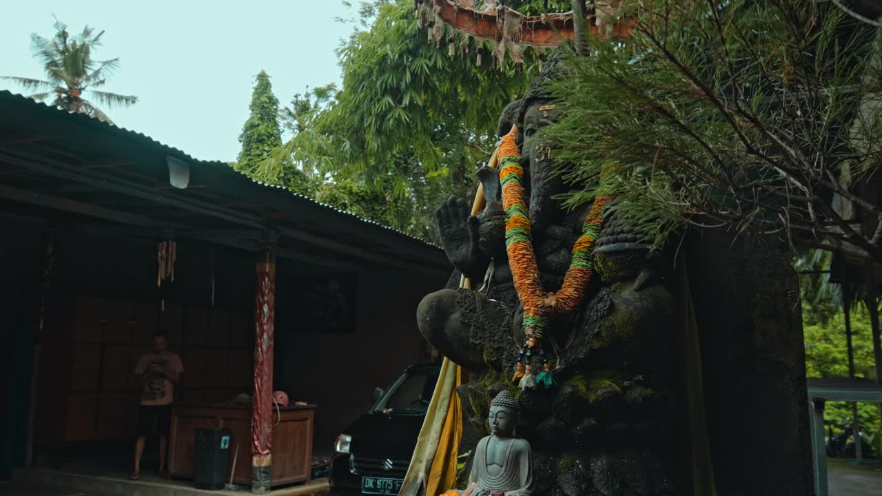 一尊古老的甘尼萨石像，浑身青苔，颈上戴着黄花花环，立在街上视频素材