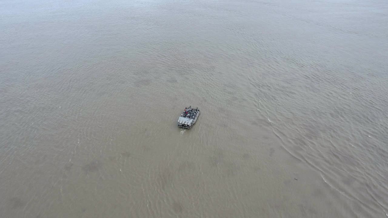 空中跟踪拍摄一艘载着乘客和摩托车横渡湄公河的小渡船视频素材