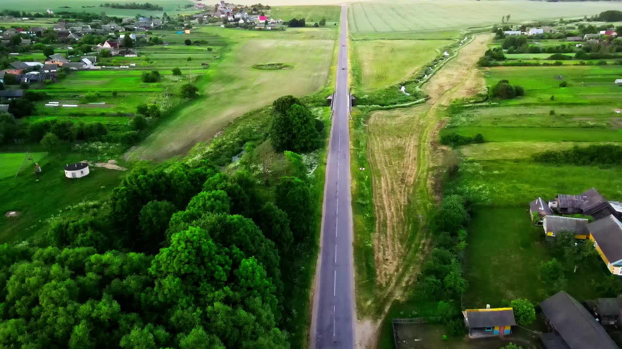 鸟瞰图的乡村道路和少量移动的汽车。郊区道路基础设施概念，绿林临路。温暖的夏日。柔和的光。视频下载