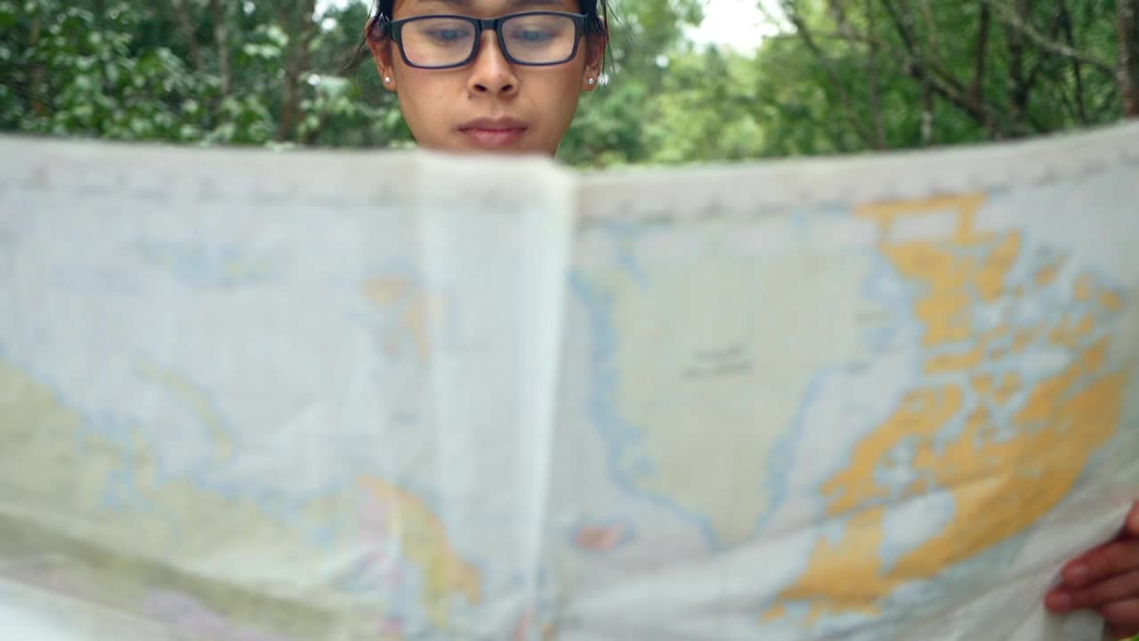 一位背包女游客在户外放松，在森林地图上寻找正确的方向。旅行和生活方式的度假概念。视频素材