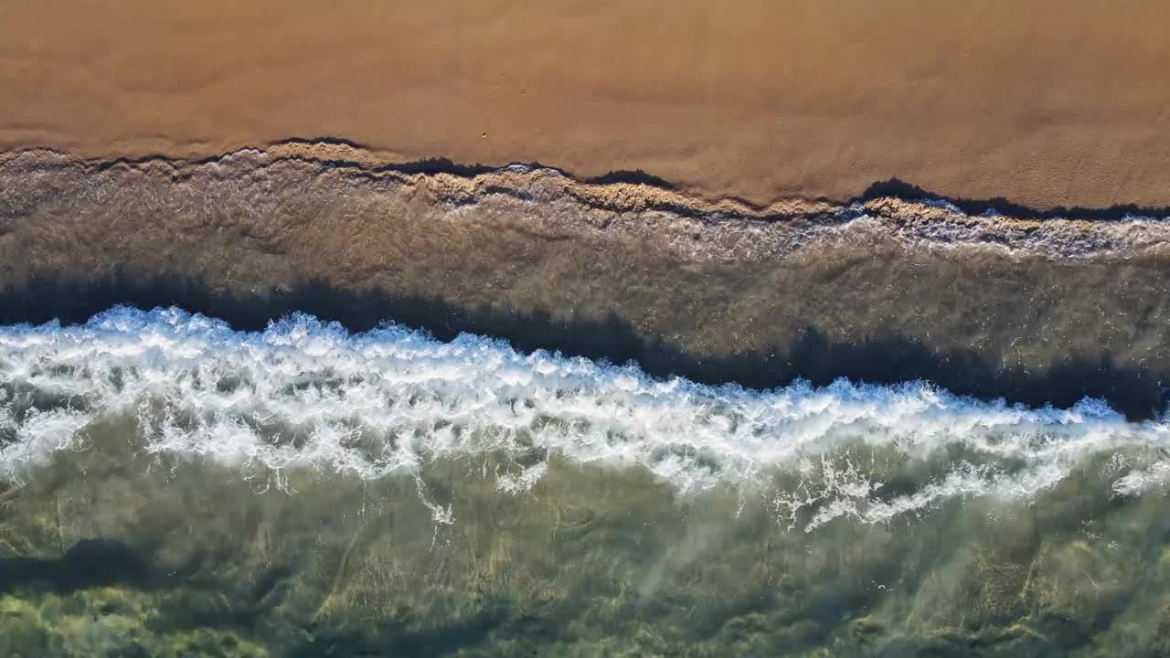 由上至下的无人机视图在安达曼海岸。海水和冲刷着海岸的大波纹充满了美丽的柔软的白色海绵。视频素材