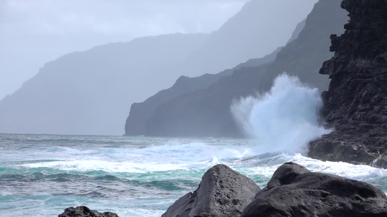 慢镜头:海水撞击火山岩石，溅向岸边。视频素材