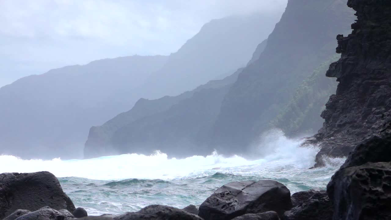 慢镜头:当海浪撞击岩石时，黑色的海岸上溅满了海水视频素材