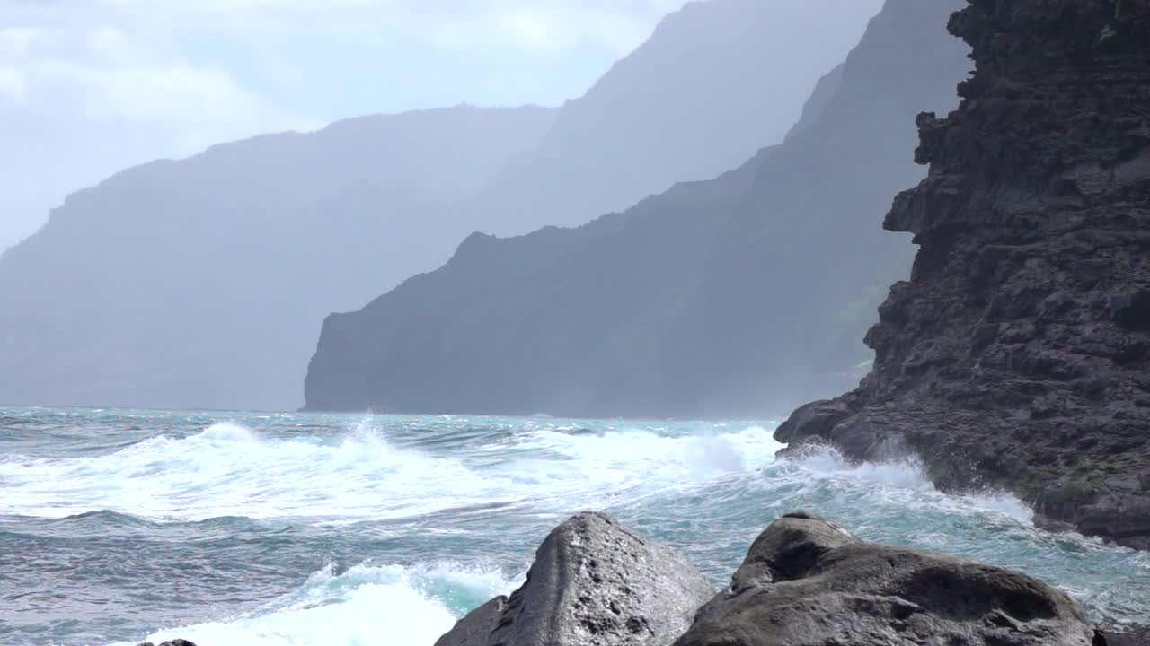 慢镜头:海水溅过考艾岛田园诗般的岩石海岸线。视频素材