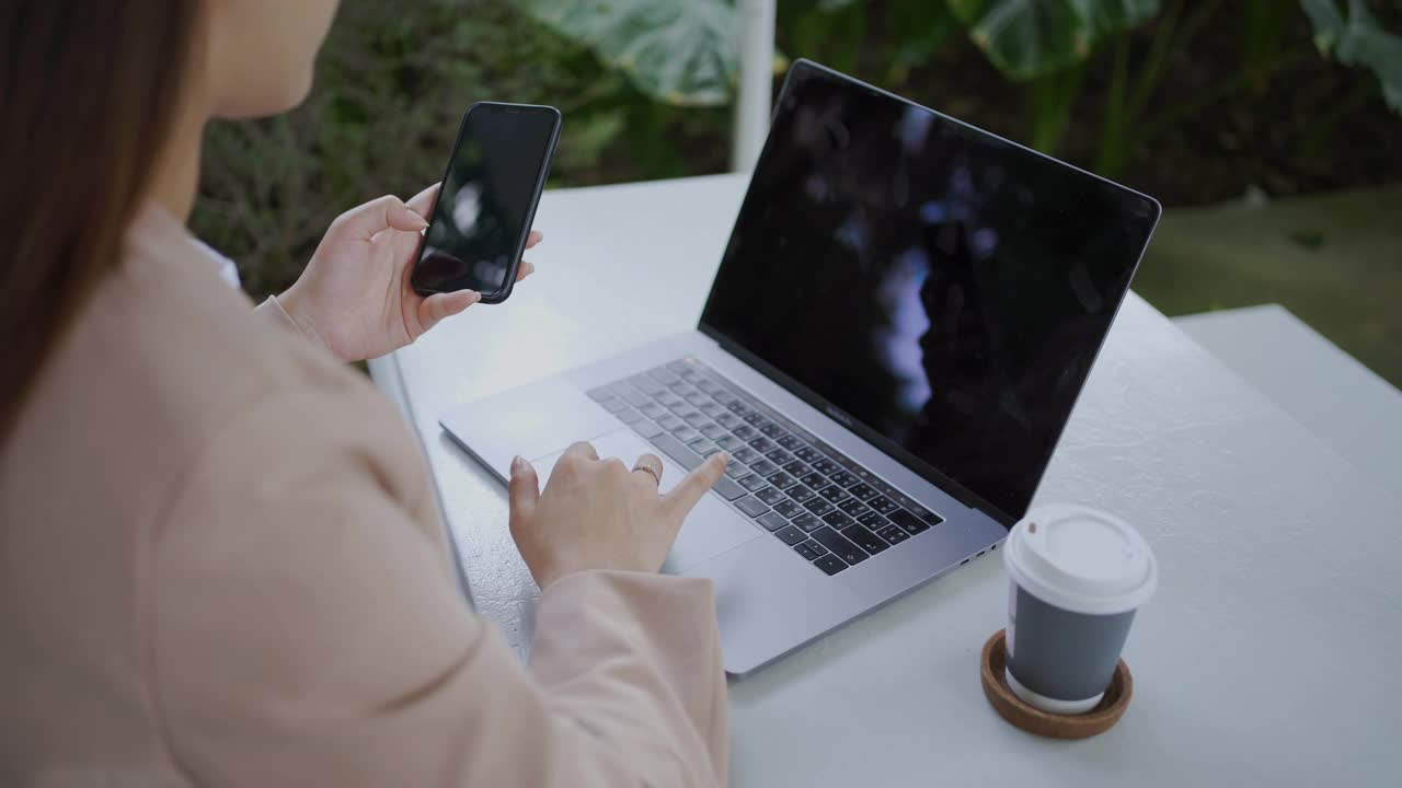 亚洲女商人在咖啡馆用笔记本电脑和智能手机工作。视频素材