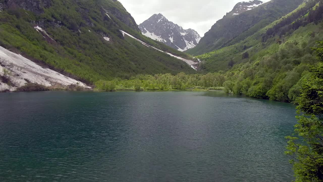 从空中俯瞰峡谷中的高山湖泊。蓝天白云映衬着美丽的山景。山里的娱乐视频下载