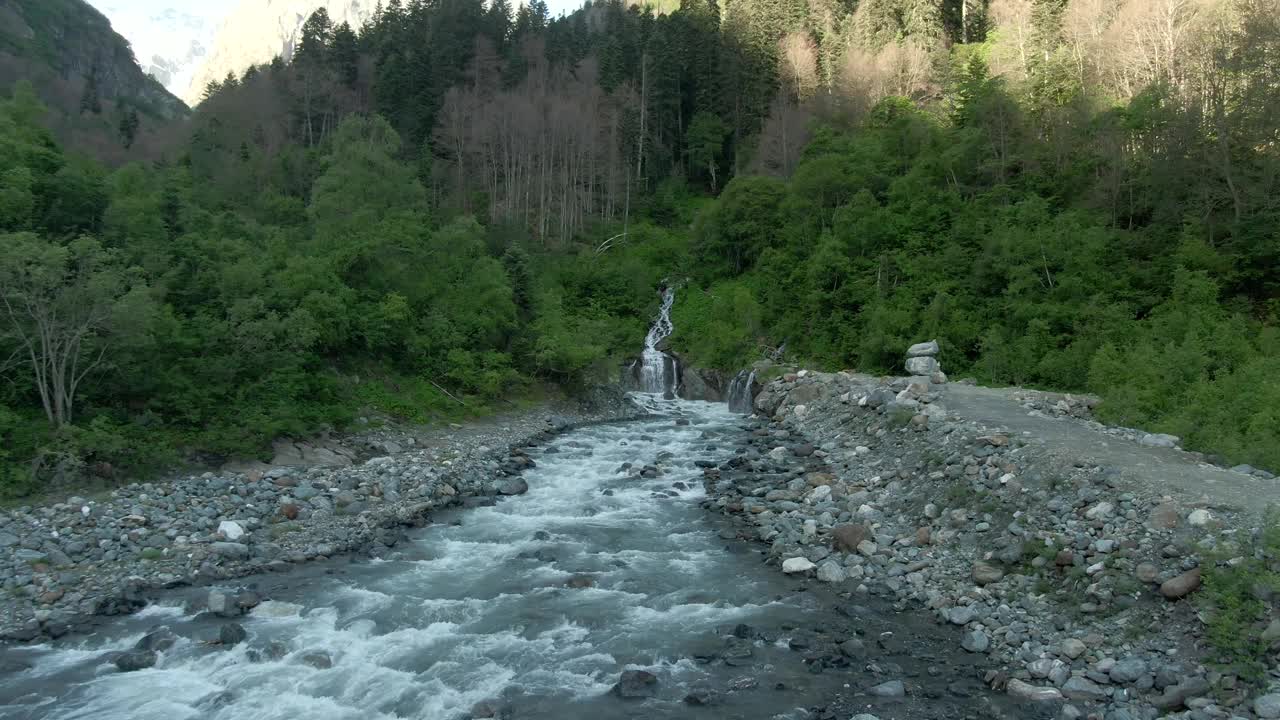 鸟瞰图飞越湍急的山河与风暴瀑布。美丽的山景，河流和瀑布的背景是绿色的森林。登山之旅视频素材