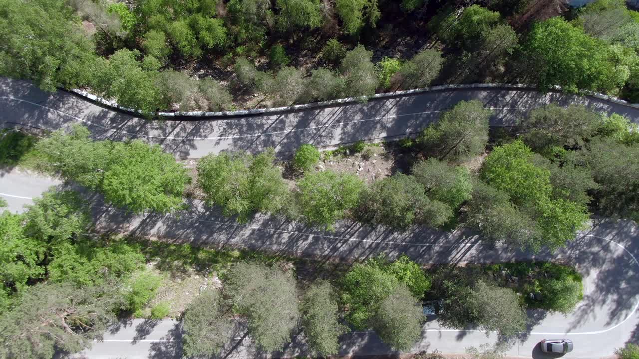 鸟瞰图:飞行在狂风暴雨的河流岸边的蜿蜒山路上。摄像机向下看。开车到山里去。视频素材